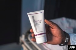 Aranmolate Ayobami, plastic surgeon at Grandville Medical and Laser clinic in Lagos, Nigeria, holds a tube of Skinlite a skin lightening product used at his clinic, July 17, 2018, in Lagos.