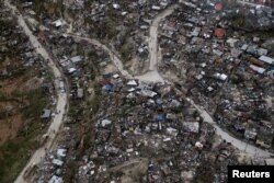 People walk down the streets next to destroyed houses after Hurricane Matthew passes Jeremie, Haiti, Oct. 5, 2016.