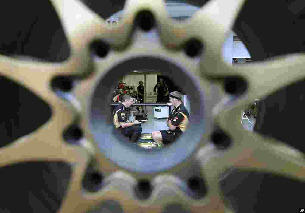 Lotus mechanics, seen through a wheel, talk to one another at the garage of the Marina Bay City Circuit in Singapore. The Formula One Singapore Grand Prix will be held on Sept. 22 in the city-state.