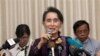 Myanmar opposition leader Aung San Suu Kyi, center, talks to journalists during a news conference at her residence, Saturday, July 11, 2015.