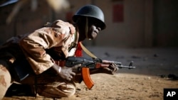 A Malian soldier takes cover behind a truck during exchanges of fire with jihadists in Gao, northern Mali, Sunday, Feb. 10, 2013.