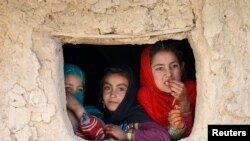 Internally displaced Afghan girls look out from their shelter at a refugee camp in Kabul, Oct. 14, 2014. 