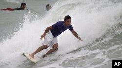 A surfer rides a wave whipped up by Tropical Storm Isaac at Haulover Beach Park in Miami Beach, Florida.