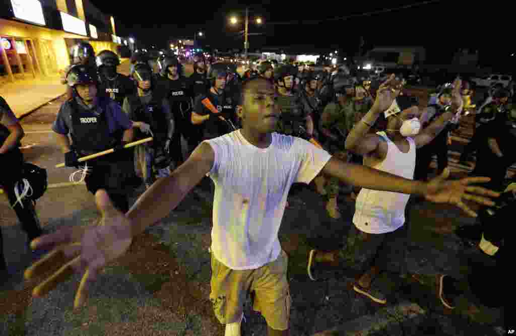 Demonstran dipindahkan oleh garis polisi saat pihak berwajib mencoba membubarkan unjuk rasa di Ferguson, Missouri (20/8). (AP/Charlie Riedel)