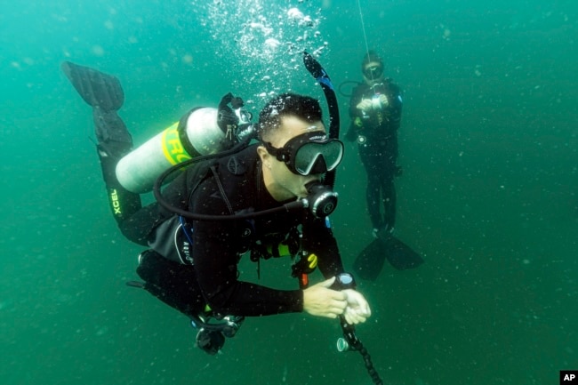 FILE - Justin Miyano, left, vessel operations coordinator, and Kimberly Roberson, research coordinator for Gray's Reef National Marine Sanctuary, make a safety stop while scuba diving at the sanctuary Monday, Oct. 28, 2019, off the coast of Savannah, Ga. (AP Photo/David J. Phillip)