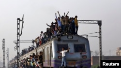 Passengers travel on an overcrowded train on the outskirts of New Delhi February 26, 2015. India will increase investment in its overloaded railway network to 8.5 trillion rupees ($137 billion) over the next five years, the government said on Thursday, pr
