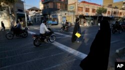 Pedestrians and motorcycles share a road in downtown Tehran, Iran, Oct. 8, 2017.