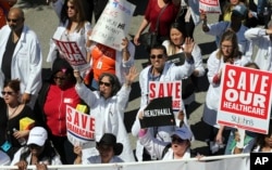 FILE - Health care professionals join hundreds of people march through downtown Los Angeles protesting President Donald Trump's plan to dismantle the Affordable Care Act, his predecessor's signature health care law, March 23, 2017.