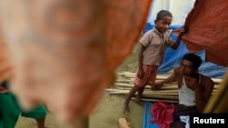 A family sits at their temporary shelter in a Rohingya refugee camp as Burma's government embarks on a national census, in Sittwe, April 2, 2014.