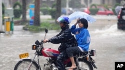 Man struggles to ride motorcycle carrying a woman during heavy rain brought by Typhoon Nesat in Qionghai, Hainan province September 29, 2011
