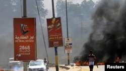 Les automobilistes passent devant des pneus en feu utilisés comme barricade alors que les manifestants se rassemblent pour faire pression sur le gouvernement à Khartoum, au Soudan, le 21 octobre 2020. REUTERS/Mohamed Nureldin Abdallah