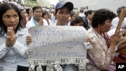 A Cambodian supporter holds a banner reading: "The court system must be respected by the public not for..." as she sits with other supporters of Mam Sonando, one of Cambodia’s most prominent human rights defenders, in front of Phnom Penh Municipal Court in Phnom Penh, Cambodia, Tuesday, Sept. 11, 2012. Some 300 supporters gathered for prayer for local radio station owner Sonando, who has been held in pre-trial detention for almost two months for insurrection charge, during his court appearance. (AP Photo/Heng Sinith)