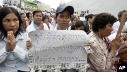 A Cambodian supporter holds a banner reading: "The court system must be respected by the public not for..." as she sits with other supporters of Mam Sonando, one of Cambodia’s most prominent human rights defenders, in front of Phnom Penh Municipal Court in Phnom Penh, Cambodia, Tuesday, Sept. 11, 2012. Some 300 supporters gathered for prayer for local radio station owner Sonando, who has been held in pre-trial detention for almost two months for insurrection charge, during his court appearance. (AP Photo/Heng Sinith)