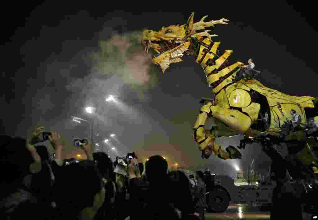 People take photos while the French production company La Machine&#39;s latest creation &quot;the Long Ma&quot; or Dragon Horse appears during a performance held in front of the Bird&#39;s Nest Stadium in Beijing, China. 