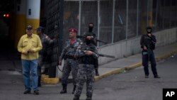 A group of Venezuelan political police officers, SEBIN, with their faces covered stand on guard at the main door of SEBIN headquarters in Caracas, Venezuela, Wednesday, May 16, 2018.