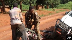 In this Sept. 16, 2013 photo, A Gabonese soldier from a regional Central African peacekeeping force helps collect the bodies of rebels who were reportedly killed by armed villagers in Njoh, Central African Republic. 