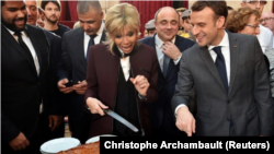 El presidente francés, Emmanuel Macron, y su esposa Brigitte cortan porciones de un tradicional pastel gigante durante una ceremonia en el Palacio del Elíseo en París, Francia, 12 de enero del 2018.