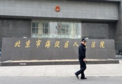 一名警察走过正在审理中国反腐败活动人士丁家喜的北京市海淀区人民法院。（2014年4月8日）