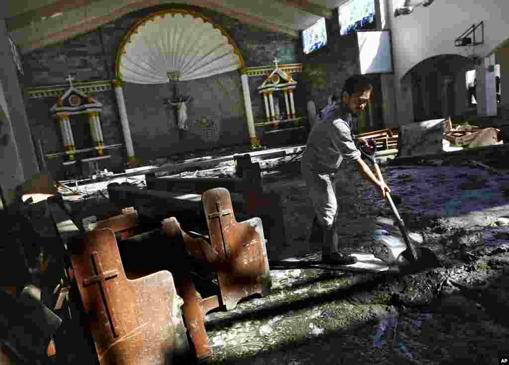 A man uses a shovel to clean up mud inside St. Joseph Parish church, which was badly damaged by Typhoon Haiyan in Tacloban, Philippines, Nov. 18, 2013. 