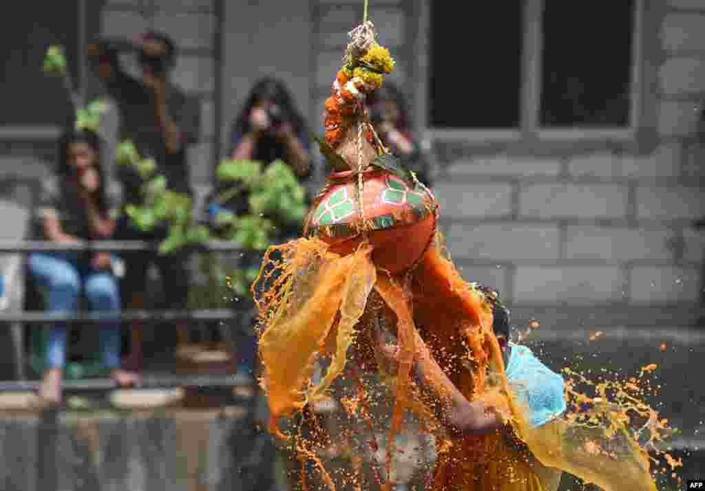 A Hindu devotee breaks a dahi-handi (curd-pot) suspended in the air atop a human pyramid during celebrations for the Janmashtami festival, which marks the birth of Hindu God Lord Krishna, in Mumbai, India.