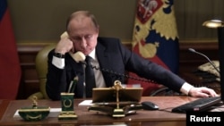 FILE - Russian President Vladimir Putin sits at a table during a telephone conversation in St. Petersburg, Russia, Dec. 15, 2018.