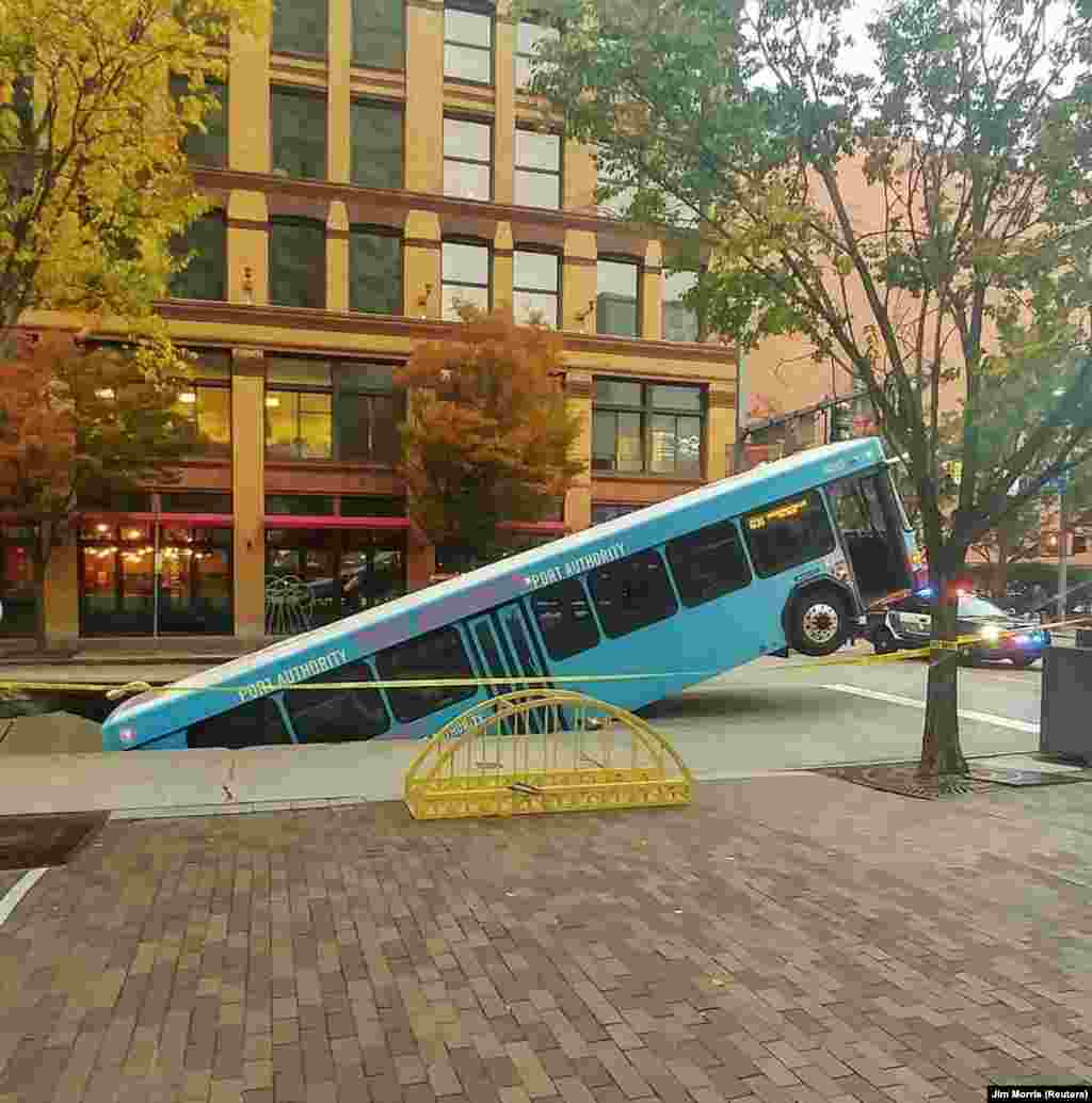 Bagian depan sebuah bus umum terperosok ke lubang pembuangan di sebuah jalan utama di kota Pittsburgh, Pennsylvania, dalam gambar yang diperoleh dari media sosial.