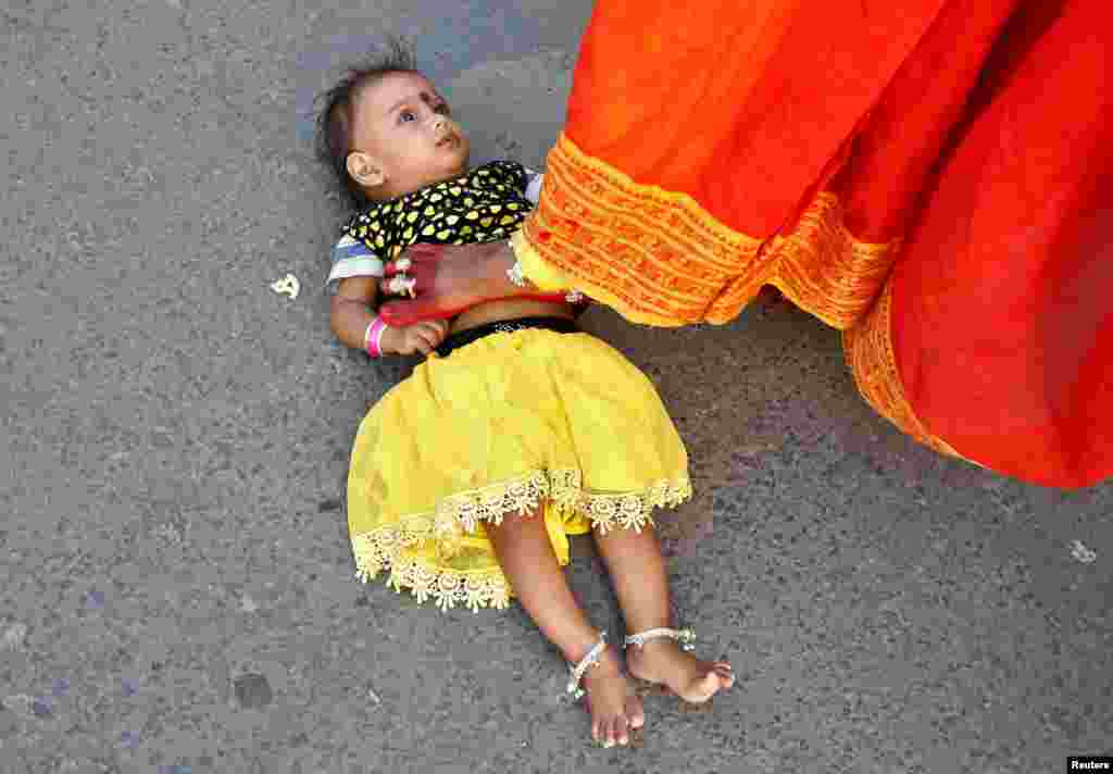 A Hindu woman steps over a child in a ritual seeking blessings for the child from the Sun god during the religious festival of Chhat Puja in Kolkata, India.