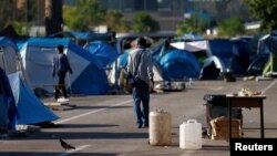 FILE - Migrants walk in a camp set by the Baobab aid group in Rome, Italy, July 12, 2018.