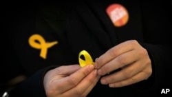 A supporter of Junts per Catalunya or Together for Catalonia makes a yellow ribbon in support of Catalonian politicians who have been jailed on charges of sedition, during a campaigning event in Barcelona, Spain, Dec. 19, 2017.
