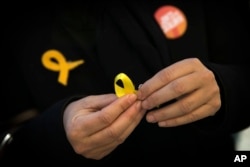 A supporter of Junts per Catalunya or Together for Catalonia makes a yellow ribbon in support of Catalonian politicians who have been jailed on charges of sedition, during a campaigning event in Barcelona, Spain, Dec. 19, 2017.