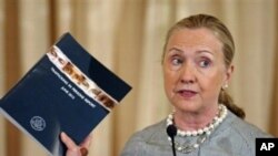 Secretary of State Hilary Rodham Clinton holds up a copy of the 2012 Trafficking in Persons Report during a ceremony marking the occasion at the State Department in Washington, Tuesday, June 19, 2012. (AP Photo/Cliff Owen)