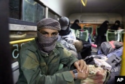 FILE - Aug. 3, 2017 photo released by the government-controlled Syrian Central Military Media, shows al-Qaida-linked militants seated in a bus with their families, after being evacuated from the town of Arsal, near the Syrian border, in northeast Lebanon