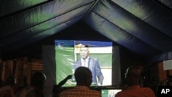 People watch on a big screen as Ivory Coast President Laurent Gbagbo talks during a live debate on national television with Ivory Coast opposition leader Alassane Ouattara in Abidjan, 25 Nov 2010