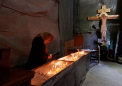 Starica pali sveće u Hramu svetog Save u Beogradu, tokom proslave Uskrsa bez prisustva vernika zbog epidemije koronavirusa, Srbija, 19. aprila 2020. (AP Photo/Darko Vojinović)