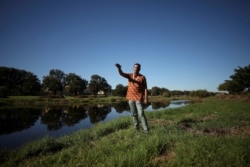 FILE - Tauriq Jenkins, who opposes a development which includes a new Africa headquarters for Amazon, stands along a river in Cape Town, South Africa, May 23, 2021.