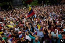 Anti-government protesters hold their hands up during the symbolic swearing-in of Juan Guaido, head of the opposition-run congress who declared himself interim president of Venezuela until elections can be called, during a rally demanding President Nicolas step down.