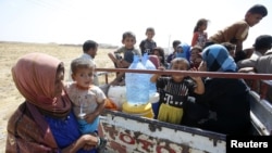 Displaced people from the minority Yazidi sect, who fled from the violence in the Iraqi town of Gwer, wait to return at a check point at the entrance of the town, Aug. 18, 2014.