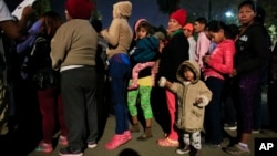 Mujeres y niños hacen fila para recibir alimentos y artículos de higiene donados en un complejo deportivo que sirve como refugio para más de 5,000 migrantes centroamericanos, en Tijuana, México, el martes 27 de noviembre de 2018.