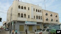 Somalis walk outside of the Dahabshil Bank in Mogadishu, Somalia, June 25, 2013.