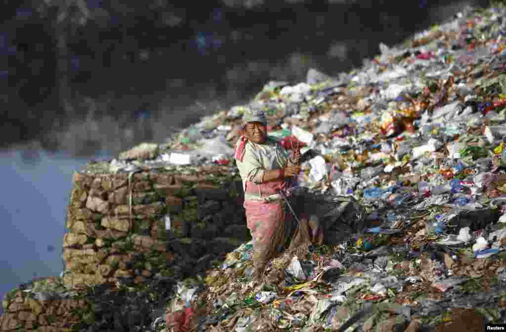 A woman searches for recyclable waste at a dump site on the banks of the Bagmati River in Kathmandu, Nepal.