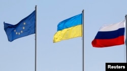 资料照片：领导人和代表团抵达期间明斯克机场外的欧盟、乌克兰与俄罗斯旗帜。(2014年8月26日)