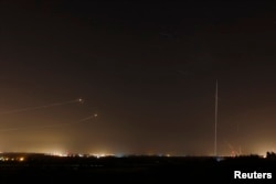 FILE - Rockets launched from the Gaza Strip towards Israel are seen (at right) as a rocket by the Iron Dome anti-missile system (at left) is fired to intercept them, before a five-day ceasefire was due to expire, August 19, 2014.