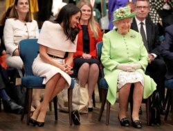 In this file photo taken on June 14, 2018 Britain's Queen Elizabeth II and Meghan, Duchess of Sussex gesture during their visit to the Storyhouse in Chester, Cheshire on June 14, 2018.
