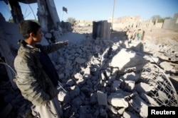 A Houthi militant shows damage at the site of a Saudi-led airstrike, north of Yemen's capital, Sanaa, March 8, 2018.