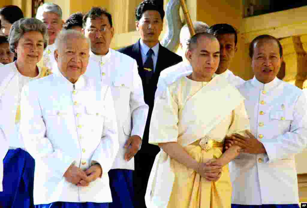 Former King Sihanouk and his son and successor King Norodom Sihamoni walk in procession at the start of coronation ceremonies at the Royal Palace in Phnom Penh, Cambodia, October 29, 2004.