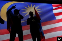 Opposition party supporters display a Malaysia national flag after Mahathir Mohamad claims the opposition party wins the General Election, broadcast on a large screen at a field in Kuala Lumpur, Malaysia, May 9, 2018.