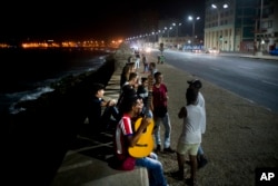 People gather along the Malecon seawall, as is customary on weekend nights, after President Raul Castro announced the death of his brother Fidel on national TV in Havana, Cuba, early Saturday, Nov. 26, 2016.