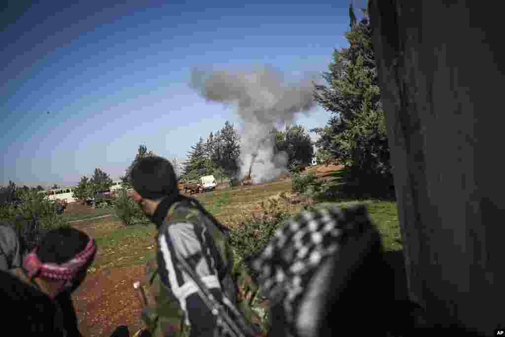 In this Saturday, Dec. 15, 2012 photo, Free Syrian Army fighters react after an explosion during heavy clashes with government forces at a military academy besieged by the rebels north of Aleppo, Syria. 