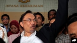 លោក Anwar Ibrahim មេដឹកនាំ​គណបក្ស​ប្រឆាំង​ម៉ាឡេស៊ី​លើក​ដៃ​ក្រោយ​ពេល​​លោក​ចេញ​ពី​តុលាការ​នៅ​ក្រុង​ Putrajaya ប្រទេស​ម៉ាឡេស៊ី​ កាល​ពី​ថ្ងៃ​ទី​៧​ខែ​មីនា ឆ្នាំ​២០១៤។