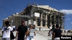 People are seen in front of the ancient Parthenon temple atop the Acropolis hill archaeological site in Athens, Greece, June 22, 2015. 